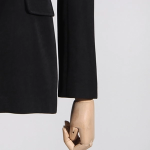 Detailed close-up of side flap pockets and premium stitching on a black blazer