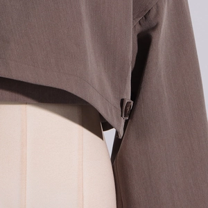 Detail of the brown cropped blazer with premium resin button closure and fine stitching