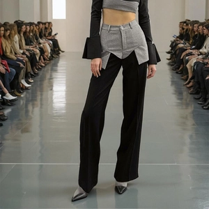 Detail of deconstructed high-waisted wide-leg trousers with grey patchwork on black fabric