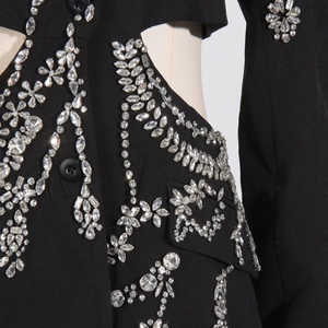 Detailed macro view of rhinestone floral embroidery and cutout on a black blazer jacket