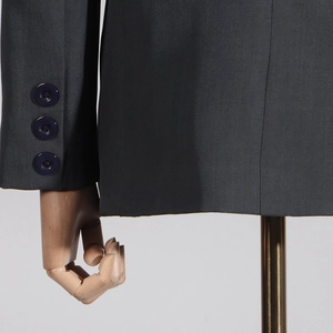 Detail of dark grey suit jacket showing sleeve buttons and fine textured fabric