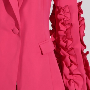 Detail eines fuchsiafarbenen Blazers mit gestuften Volants am Ärmel und glatter Tasche