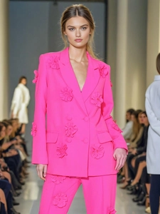 Bright pink double-breasted suit for women featuring 3D floral accents on the catwalk