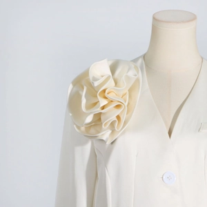 Detail of elegant cream blazer featuring a large 3D floral appliqué on the shoulder