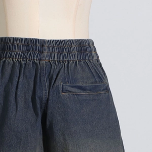 Detail of dark blue denim shorts featuring elastic waistband and rear pocket on a mannequin