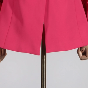 Detailansicht des hinteren Schlitzes am Saum der leuchtend rosa ausgestellten Hose