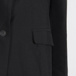 Détail d'un blazer noir avec bouton en résine et poche à rabat sur tissu de qualité
