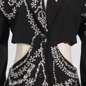 Close-up of luxury black blazer featuring heavy rhinestone floral patterns and waist cut-out