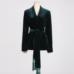Detail of forest green velvet blazer featuring shawl lapel and fringed belt waist tie