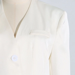Detailed view of white lightweight blazer featuring a V-neckline and decorative welt pocket