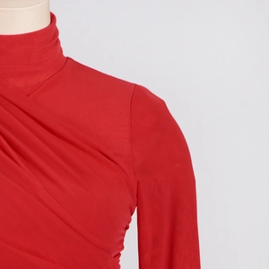 Detail of red mock neck top with elegant crisscross pleated design and stretchy fabric