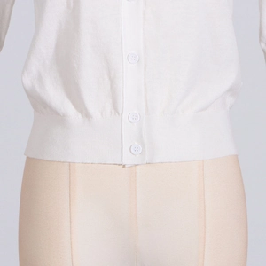 Detailed view of the white knitted cardigan showing round buttons and ribbed hem texture