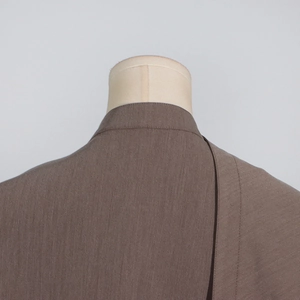 Detail of the taupe blazer lapel showing fine fabric texture and premium stitching