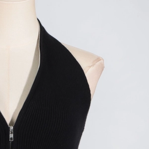 Detailed view of black ribbed knit halter top featuring a functional silver neck zipper