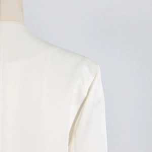 Close-up of white trench coat shoulder with smooth woven fabric and clean tailored seams