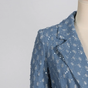 Détails d'une veste en jean bleue avec sequins, bords effilochés et franges à l'épaule