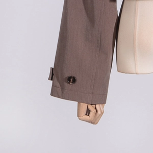 Detailed close-up of brown suit jacket sleeve with amber button and textured fabric