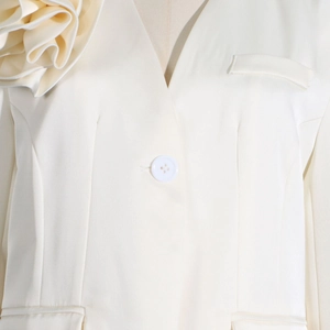 Detail of elegant cream blazer featuring a large 3D fabric flower on shoulder