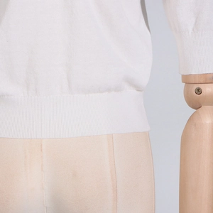 Detail shot of the ribbed cuffs and hem on this elegant white knitted top for women