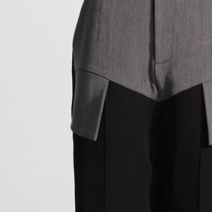 Detail of grey and black patchwork trousers with asymmetrical deconstructed design