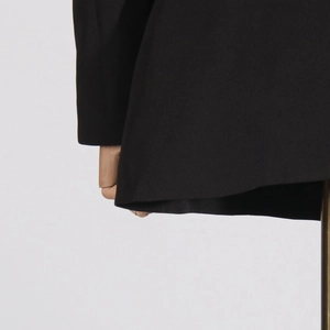 Detail of tailored black blazer sleeve with precise stitching on a wooden mannequin
