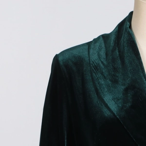 Close-up of deep green velvet blazer shoulder showing premium texture and tailoring