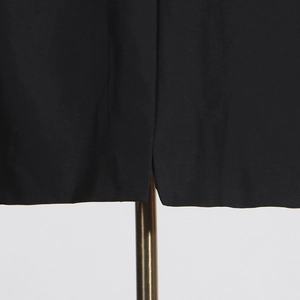 Détail de la fente précise sur l'ourlet du blazer noir avec une texture de tissu premium