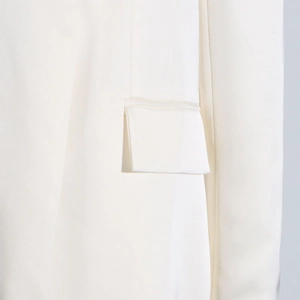 Close-up of white trench coat pocket with refined stitching and minimalist flap detail