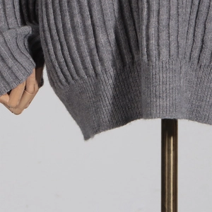 Detail of grey ribbed knit sweater hem and cuffs showing soft vertical knit texture