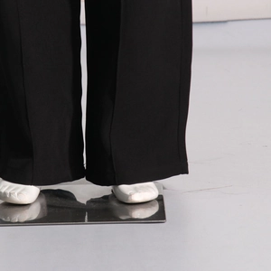 Detailed macro view showing the hem and premium fabric texture of black wide-leg trousers