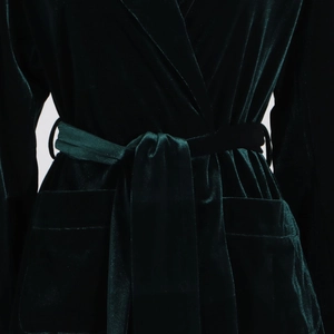Detailed close-up of dark green velvet blazer featuring waist tie belt and patch pocket