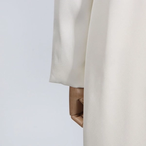 Detailed close-up of the white trench coat sleeve cuff showing high-quality woven fabric