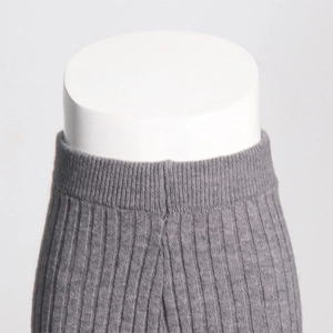 Detail of grey ribbed knit trousers showing elastic high waist and vertical texture