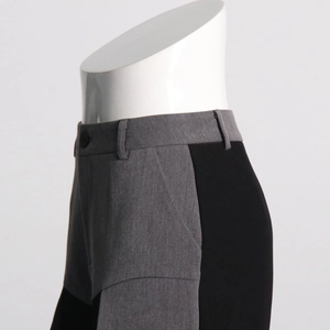 Detail of color-block casual trousers showing waist design and grey-black patchwork fabric