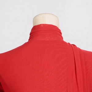 Detail of red mock neck mesh top showing draped shoulder pleats and sheer fabric texture