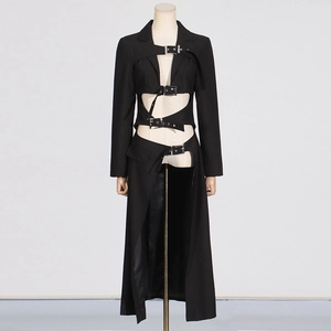 Detail view of black long trench coat featuring geometric cut-outs and metal buckles