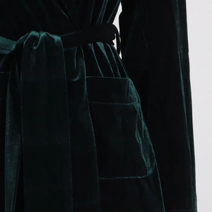 Detail of dark green velvet robe featuring a side patch pocket and tie-waist belt