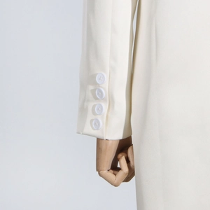 Close-up of ivory trench coat sleeve with four elegant buttons on smooth woven fabric