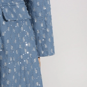 Gros plan détaillé sur du denim bleu clair vieilli avec des paillettes argentées