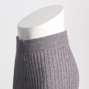 Detail of dark grey ribbed knit trousers with high elastic waist on a white mannequin