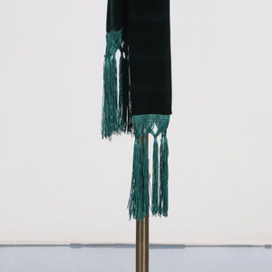 Detail of dark green velvet blazer featuring thick fringe tassels and a glossy texture