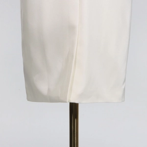 Close-up of white satin trench coat hem featuring a sleek overlap vent and pearl luster