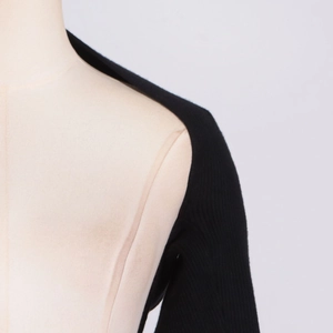 Close-up of premium black knit fabric texture and shoulder detail on a model