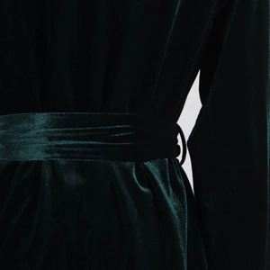 Detail of dark green velvet blazer showing fabric texture and matching waist tie design