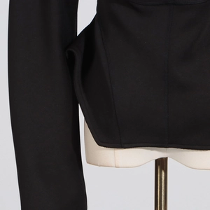 Detail of structured waist tailoring and stitching on a black fitted jacket