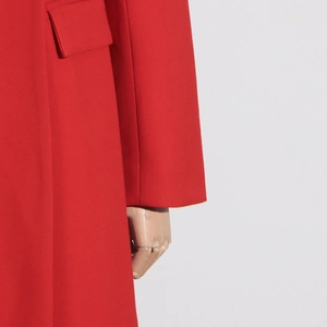 Détail d'un manteau rouge en laine montrant le rabat de la poche et les finitions premium