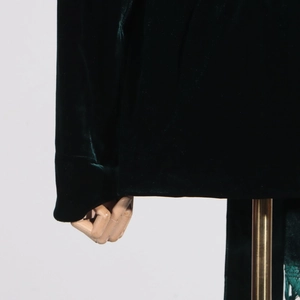 Detailed macro view of dark green velvet blazer fabric with luxury texture and sheen