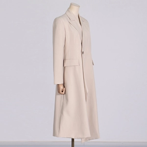 Detailed view of beige long trench coat featuring classic lapel and flap pockets detail