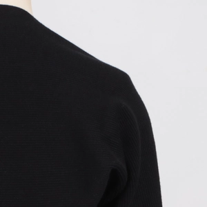 Close-up detail of high-quality black ribbed knit fabric and shoulder tailoring