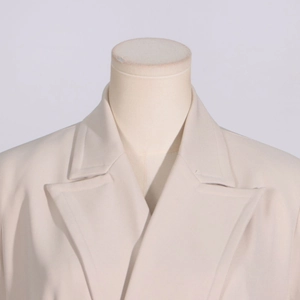 Detail of classic notched lapel and shoulder tailoring on a light beige trench coat
